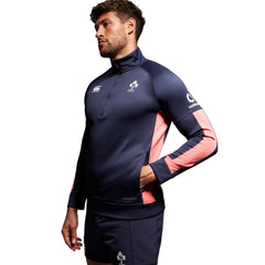 Felpa Rugby Irlanda Thermoreg 2023-24 Blu-Rosa: Maglia da allenamento da rugby irlandese blu navy e rosa con zip a un quarto, con logo della squadra e marchio dello sponsor.