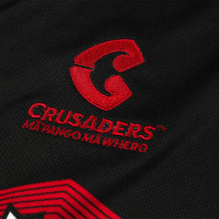 Maglia da trasferta Crusaders Super Rugby Pacific 2024-25: maglia da rugby nera con logo Crusaders ricamato in rosso e dettagli della squadra.