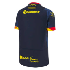 Maglia da rugby da trasferta dei Dragons Catalans 2023-24: maglia da rugby blu navy con dettagli gialli e rossi. Kit ufficiale da trasferta.