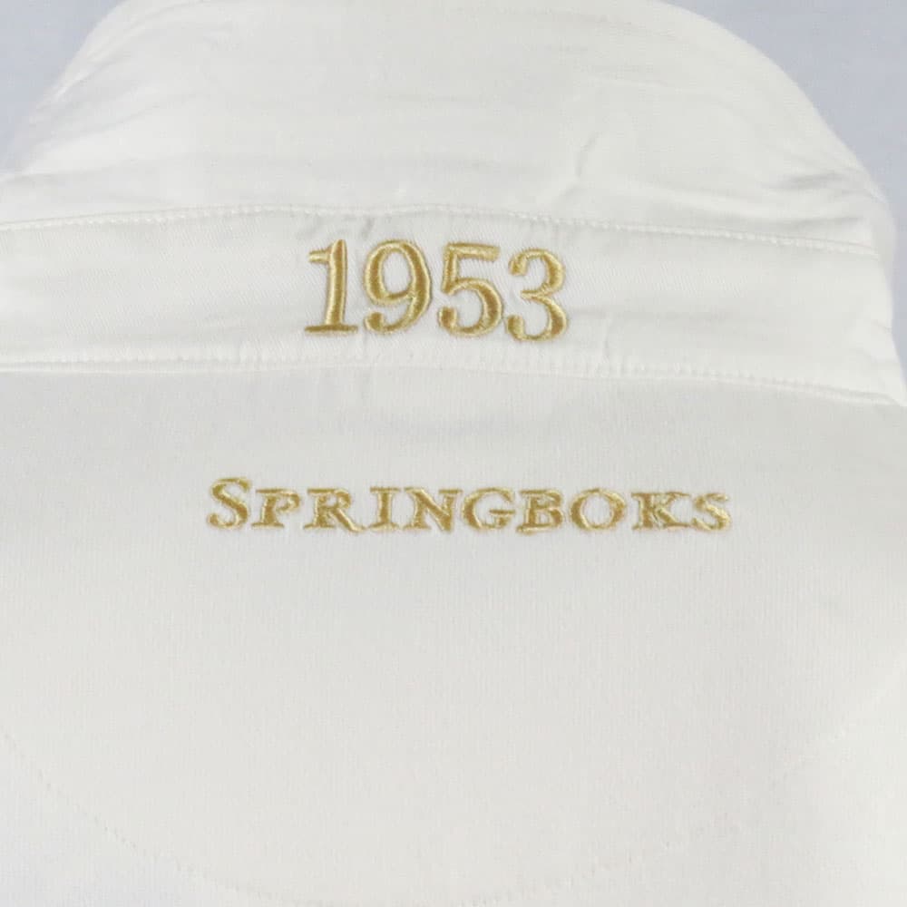 Maglia da rugby vintage degli Springboks del 1953: maglia da rugby sudafricana bianca con dettagli ricamati in oro con la scritta "1953" e la scritta "Springboks".