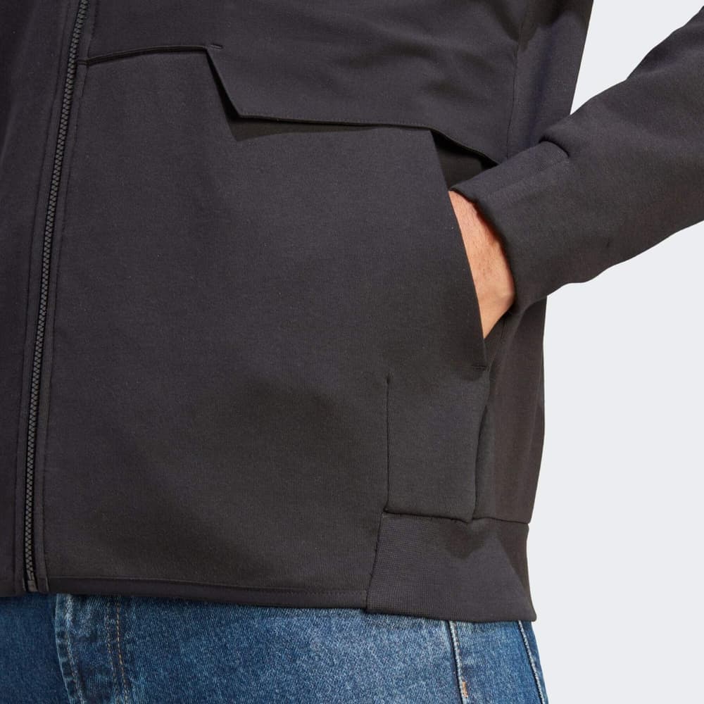 Giacca Anthem Adidas All Blacks nera, dettaglio tasca con zip e mano inserita.