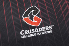 Felpa Rugby Crusaders 2026 con logo ricamato e scritte in bianco su sfondo nero e righe rosse.