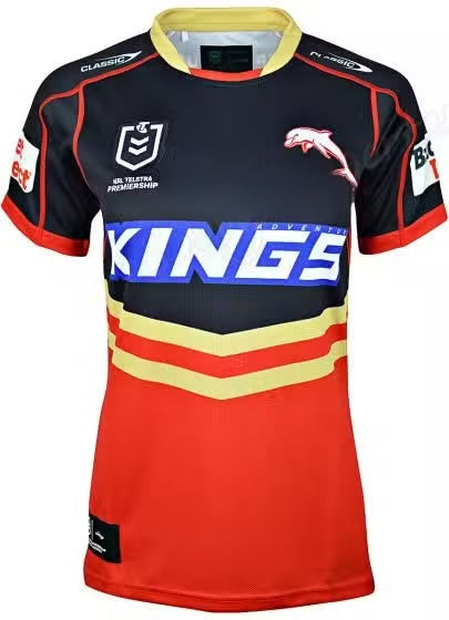 Maglia alternativa per bambini dei Redcliffe Dolphins NRL: maglia da rugby rossa e nera con logo della squadra e dettagli degli sponsor.