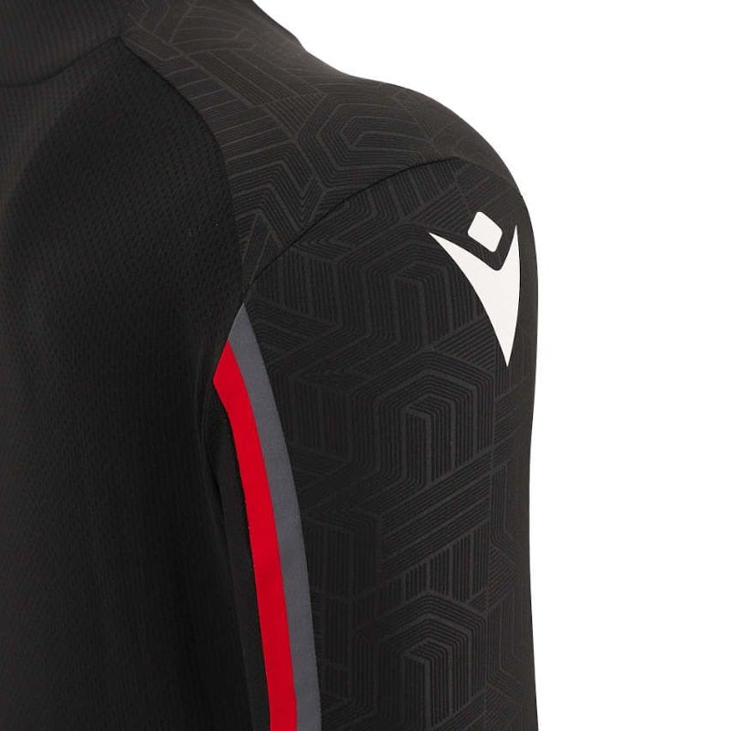 T-shirt Galles Training Staff Poliestere nero: maglietta da allenamento in poliestere nero con dettagli rossi e grigi, caratterizzata da un motivo geometrico e dal logo della squadra.