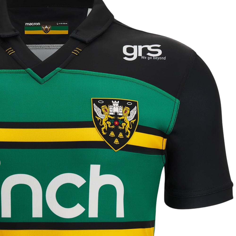Maglia da rugby casalinga dei Northampton Saints 2023: maglia da professionista verde e nera con strisce gialle, stemma della squadra e logo Macron.